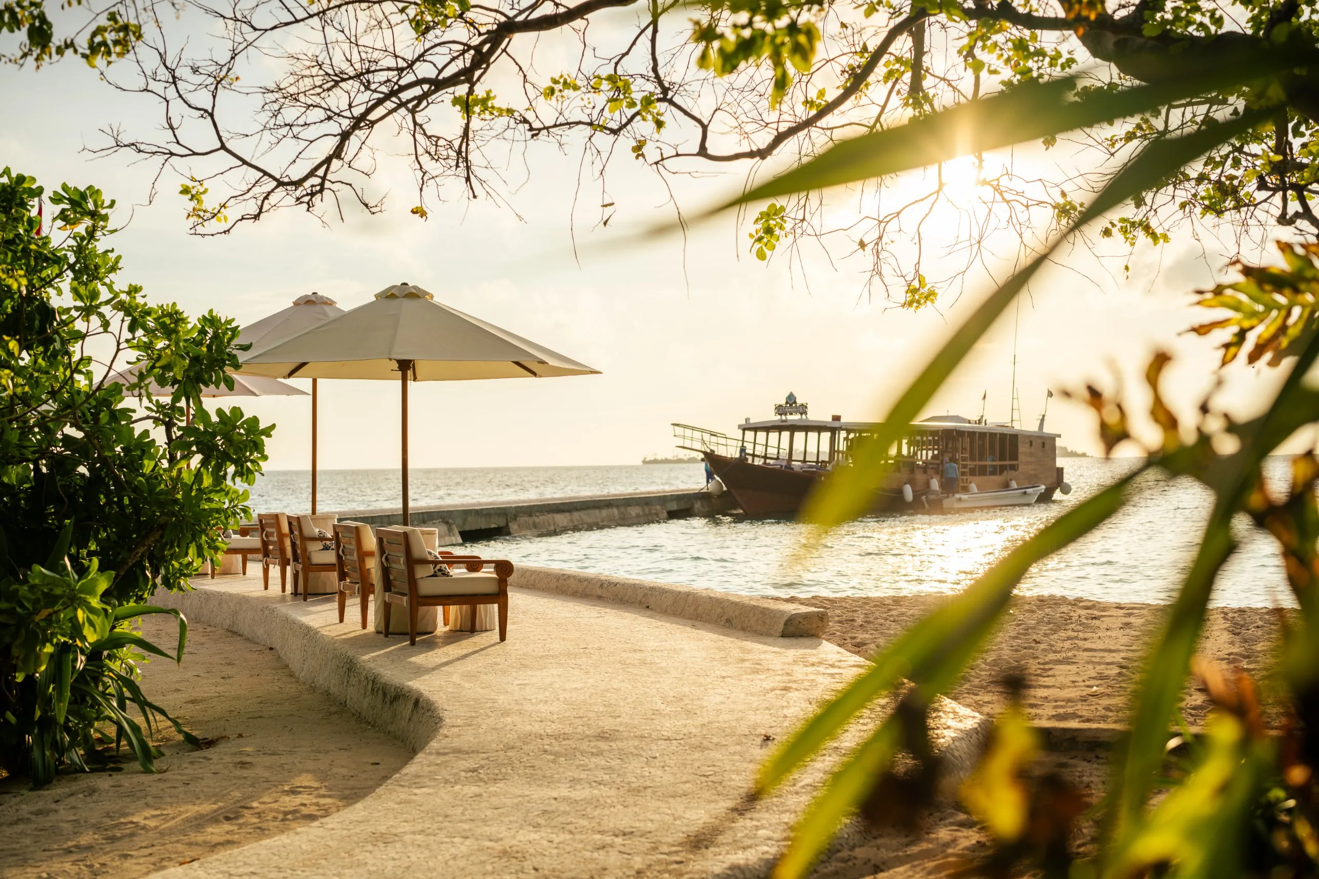 Shaded seating by the water at Wakatobi, with the jetty and boat in the background