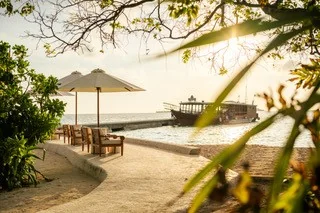 Shaded seating by the water at Wakatobi, with the jetty and boat in the background